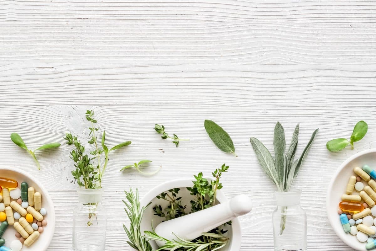 Fresh herbs and supplements on a white wooden table